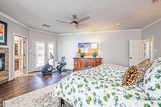 bedroom with ceiling fan, crown molding, wood-type flooring, a textured ceiling, and a tiled fireplace