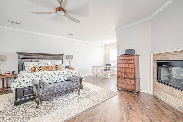 bedroom with hardwood / wood-style floors, ceiling fan, ornamental molding, and a fireplace