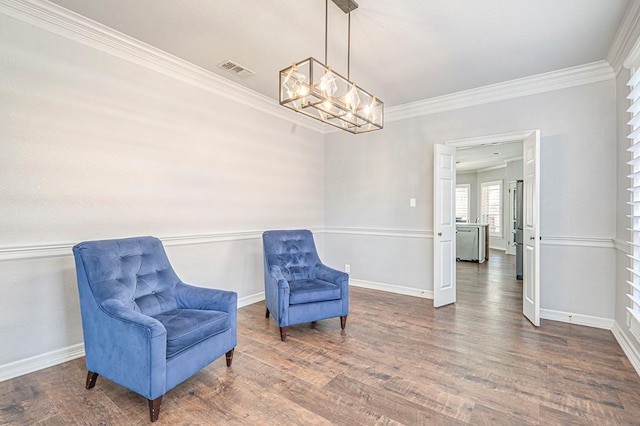 sitting room featuring dark hardwood / wood-style floors, ornamental molding, and an inviting chandelier