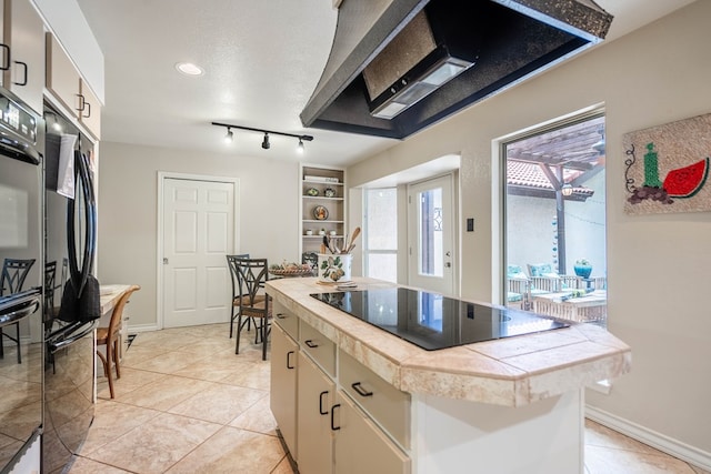 1115 Gulf Ave, Midland, TX 79705 - kitchen featuring black electric cooktop, a kitchen island, light tile patterned floors, baseboards, and tile countertops