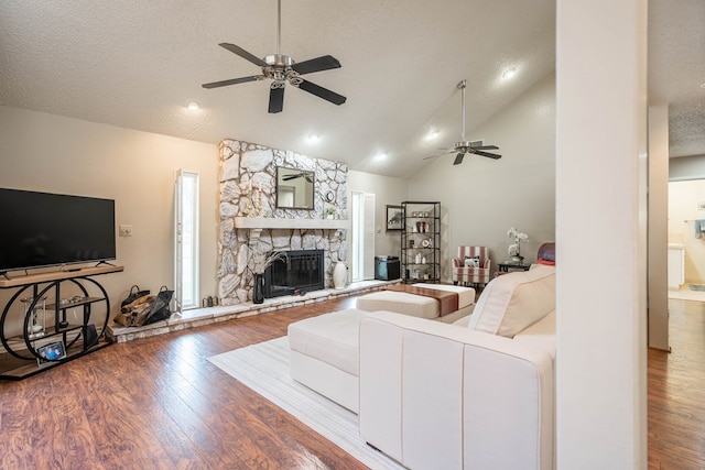 1115 Gulf Ave, Midland, TX 79705 - living room with a ceiling fan, wood finished floors, a stone fireplace, a textured ceiling, and high vaulted ceiling