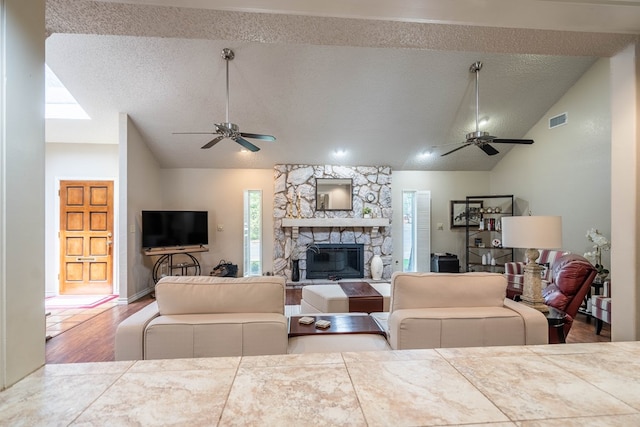 1115 Gulf Ave, Midland, TX 79705 - living area featuring ceiling fan, lofted ceiling, wood finished floors, a textured ceiling, and a stone fireplace