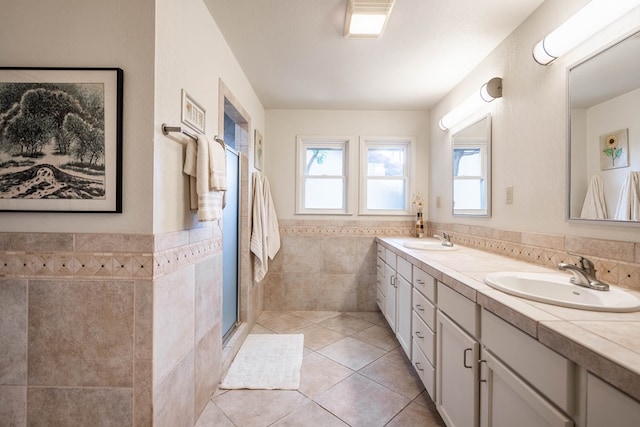 1115 Gulf Ave, Midland, TX 79705 - full bathroom featuring tile walls, double vanity, tile patterned flooring, a wainscoted wall, and a stall shower