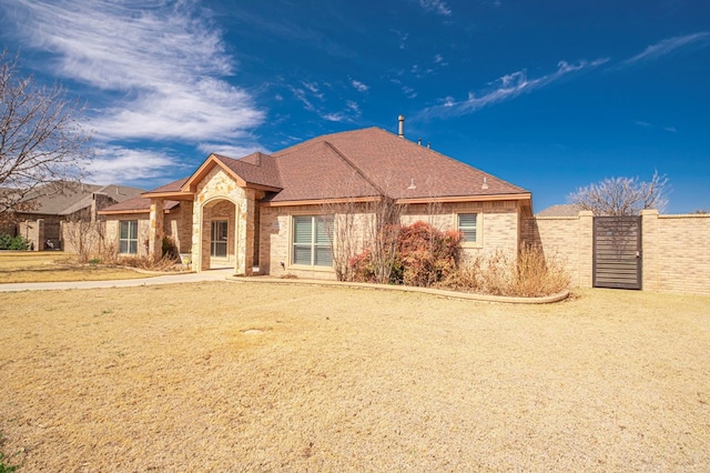 ranch-style home with a shingled roof, stone siding, and brick siding