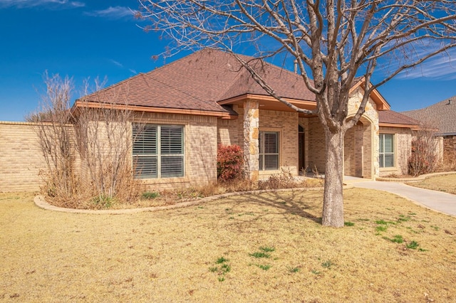 ranch-style home with driveway, a shingled roof, a front lawn, and brick siding