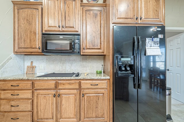 kitchen with light tile patterned floors, black appliances, tasteful backsplash, and light stone countertops