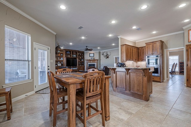 dining area featuring ceiling fan, recessed lighting, a fireplace, and crown molding