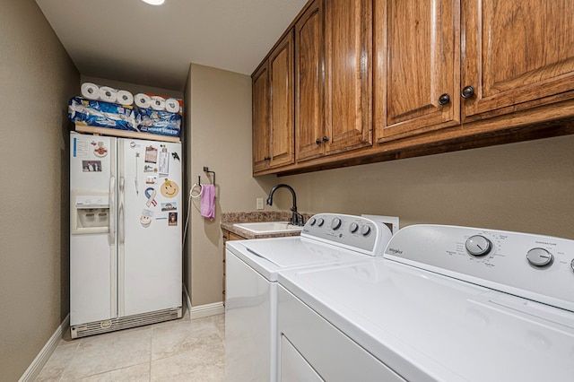 washroom featuring independent washer and dryer, cabinet space, a sink, and baseboards