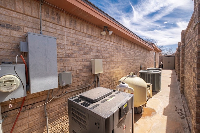 view of property exterior with central AC and brick siding