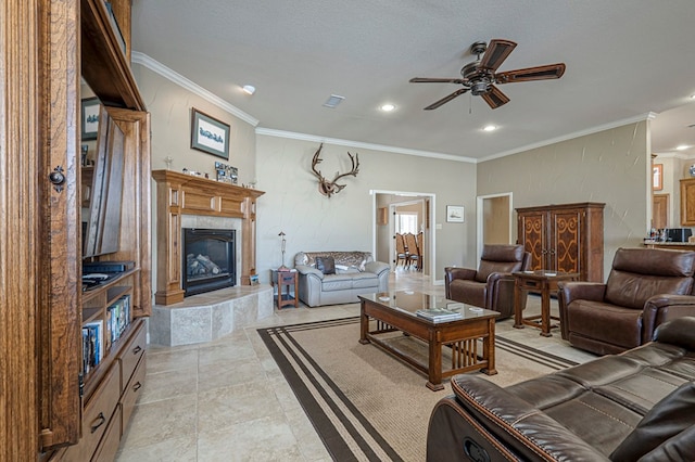 living area featuring a ceiling fan, a fireplace, visible vents, and crown molding