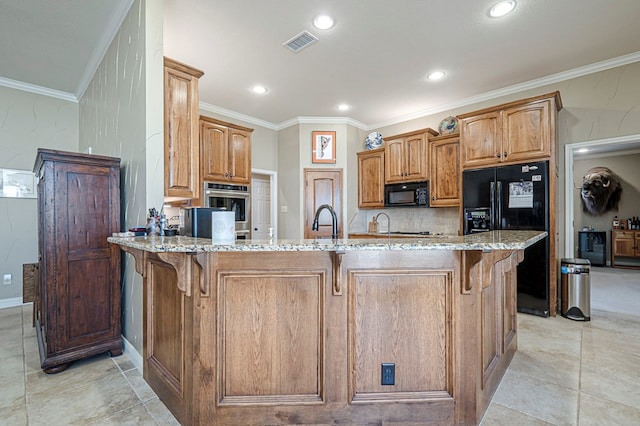 kitchen with light stone counters, a breakfast bar area, a sink, visible vents, and black appliances