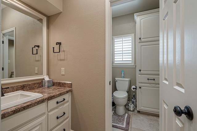 bathroom with a textured wall, vanity, and toilet