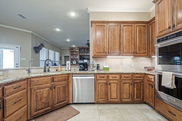 kitchen featuring stainless steel appliances, brown cabinets, crown molding, and a sink