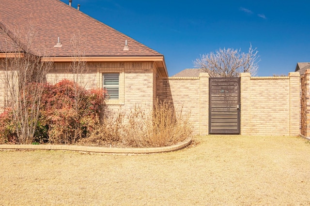 view of side of home featuring roof with shingles and brick siding