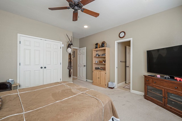 bedroom with light carpet, a ceiling fan, baseboards, and a closet