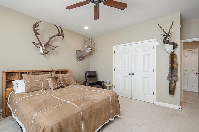 bedroom featuring a closet, light colored carpet, ceiling fan, and baseboards