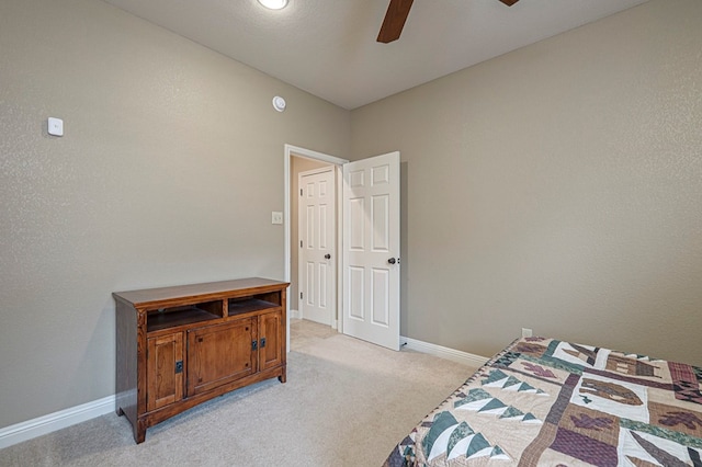 bedroom featuring light carpet, a ceiling fan, and baseboards