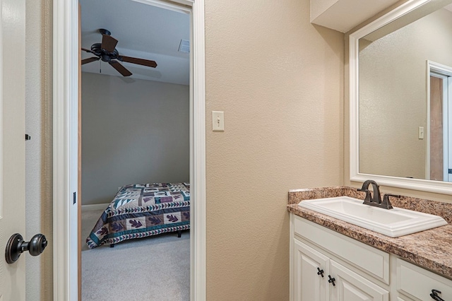 ensuite bathroom featuring ceiling fan, a textured wall, visible vents, vanity, and ensuite bath