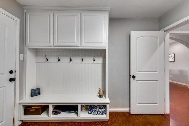 mudroom featuring arched walkways, baseboards, and finished concrete flooring
