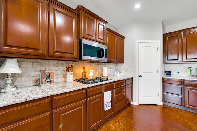kitchen with recessed lighting, light stone counters, backsplash, stainless steel microwave, and black gas stovetop