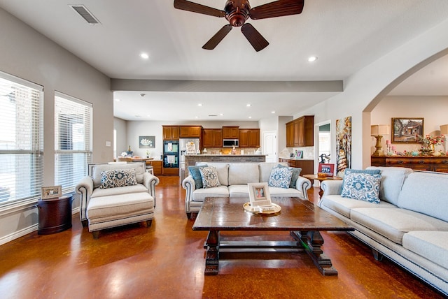 living area featuring arched walkways, a ceiling fan, visible vents, and recessed lighting