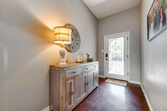 entrance foyer with concrete floors, a textured wall, and baseboards