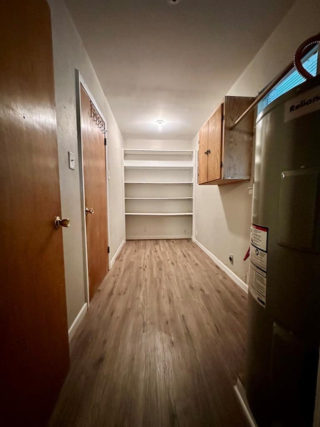 spacious closet featuring water heater and light hardwood / wood-style floors