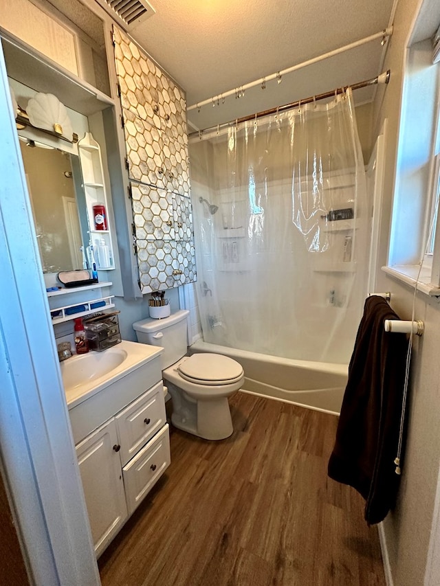 full bathroom featuring wood-type flooring, vanity, toilet, shower / bath combo, and a textured ceiling