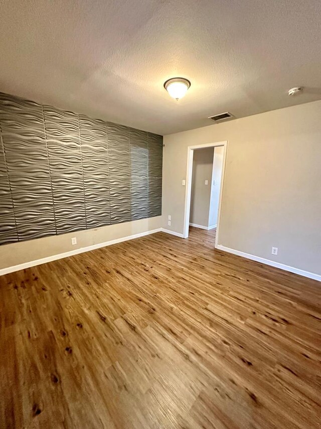 spare room featuring hardwood / wood-style floors and a textured ceiling