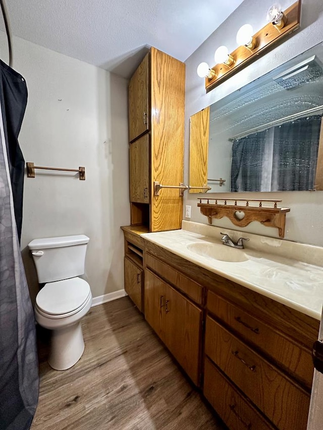 bathroom with wood-type flooring, toilet, vanity, and a textured ceiling