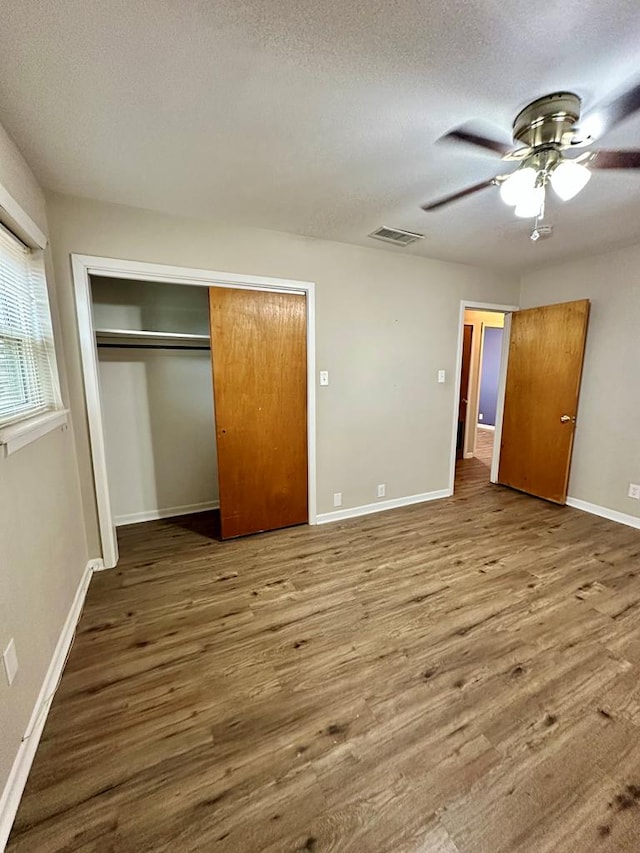 unfurnished bedroom with hardwood / wood-style flooring, ceiling fan, a closet, and a textured ceiling