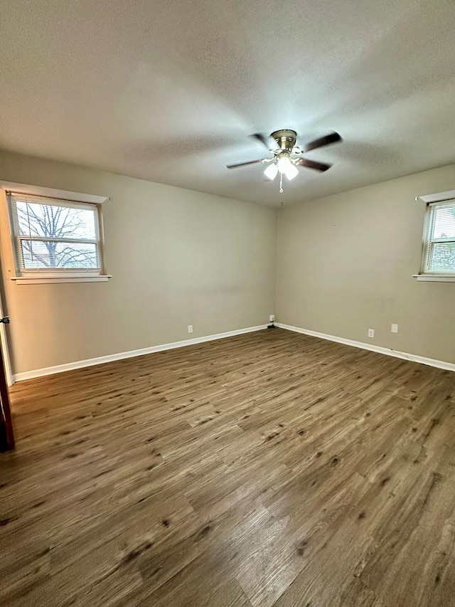 spare room with ceiling fan, dark wood-type flooring, a textured ceiling, and plenty of natural light