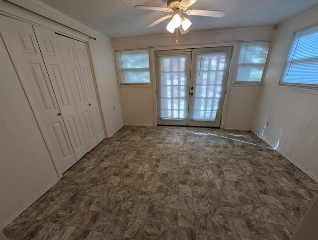 unfurnished bedroom with crown molding, french doors, a textured ceiling, a ceiling fan, and a closet