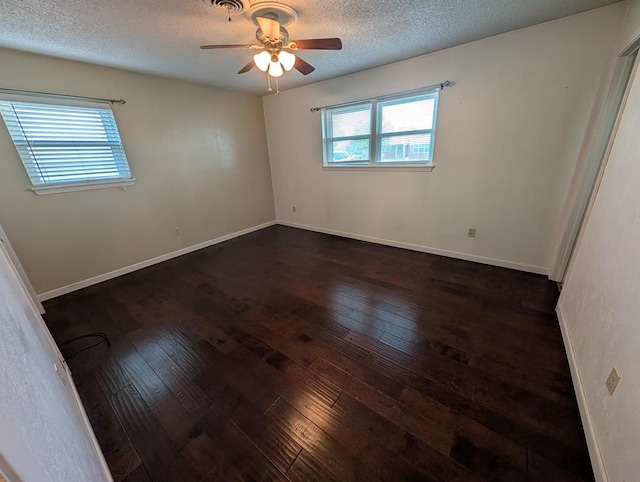 spare room with dark wood-type flooring, plenty of natural light, a ceiling fan, and a textured ceiling