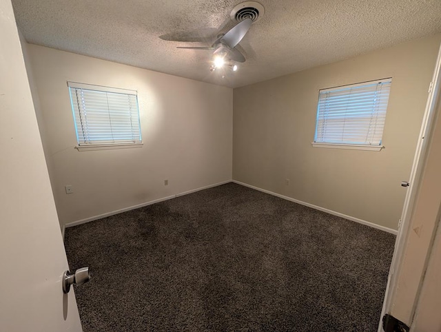 empty room with ceiling fan, a textured ceiling, dark carpet, and baseboards