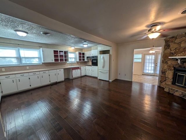 kitchen with freestanding refrigerator, white cabinets, dark wood-type flooring, and ceiling fan