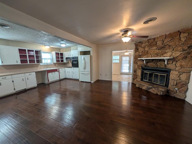 unfurnished living room featuring a sink, ceiling fan, dark wood-type flooring, and healthy amount of natural light