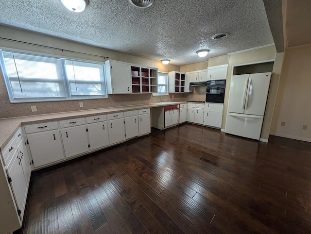 kitchen with freestanding refrigerator, oven, white cabinetry, extractor fan, and a sink