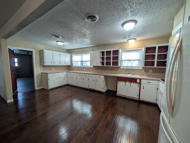 kitchen featuring freestanding refrigerator, open shelves, a sink, dark wood-style flooring, and a textured ceiling
