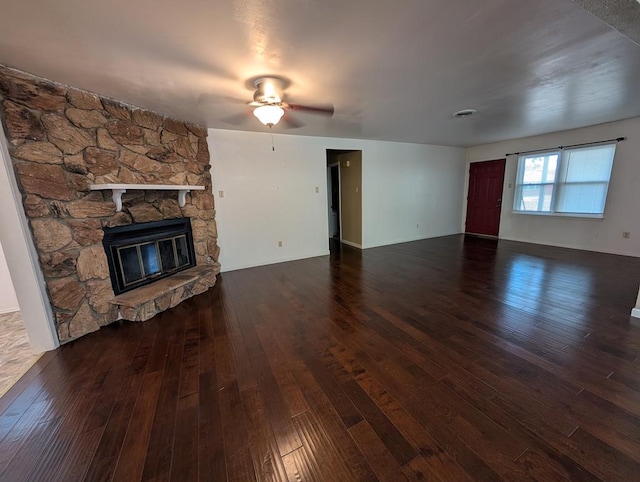 unfurnished living room with hardwood / wood-style flooring, a ceiling fan, and a stone fireplace