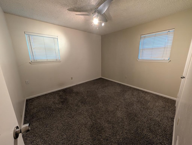 empty room with ceiling fan, dark carpet, a textured ceiling, and baseboards
