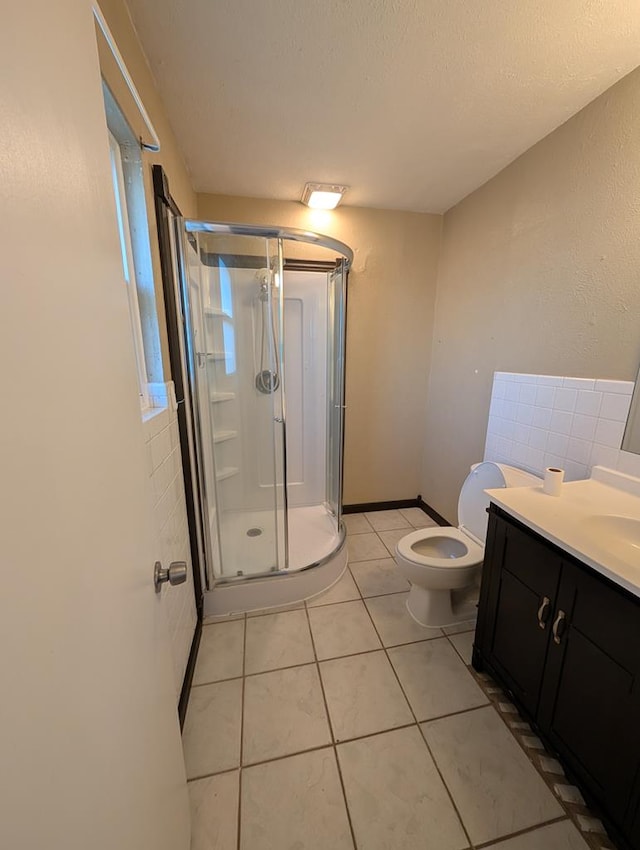 bathroom featuring a stall shower, vanity, toilet, and tile patterned floors