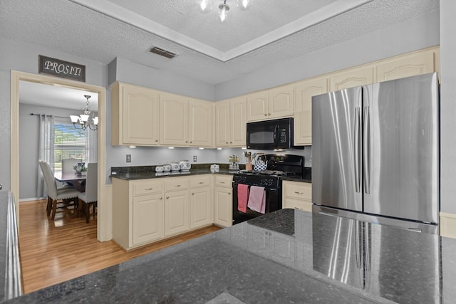 2821 Goddard Pl, Midland, TX 79705 - kitchen with black appliances, a chandelier, cream cabinets, dark stone counters, and a textured ceiling