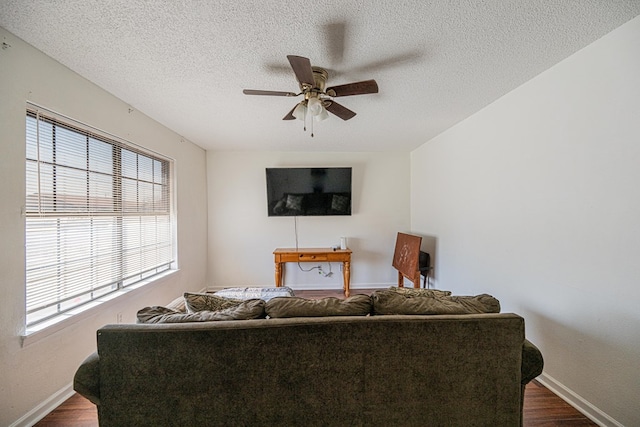 living room featuring baseboards, ceiling fan, and dark wood-style flooring