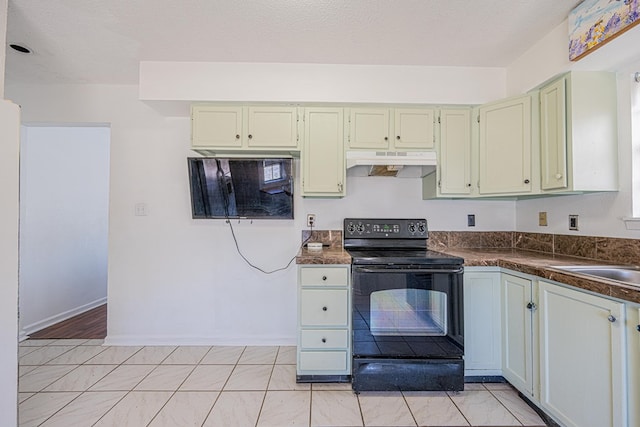 kitchen with dark countertops, under cabinet range hood, black electric range oven, a textured ceiling, and a sink