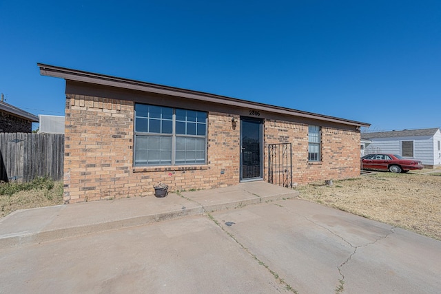 rear view of house featuring brick siding and fence