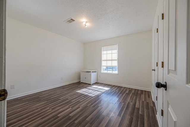 unfurnished bedroom with baseboards, visible vents, dark wood-style flooring, and a textured ceiling