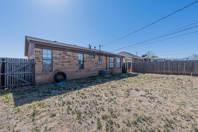 rear view of house featuring brick siding and fence