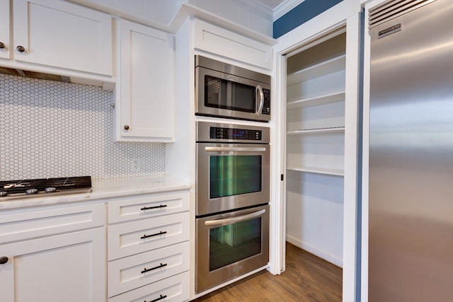 709 21st St, Lamesa, TX 79331 - kitchen with appliances with stainless steel finishes, light countertops, tasteful backsplash, white cabinetry, and light wood-style flooring