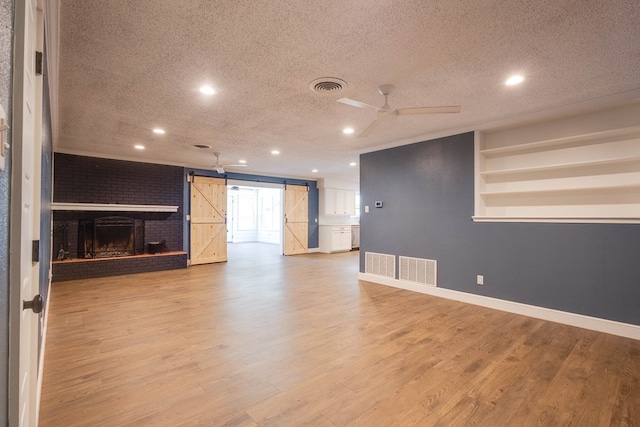 709 21st St, Lamesa, TX 79331 - unfurnished living room with a barn door, a textured ceiling, recessed lighting, light wood finished floors, and ceiling fan